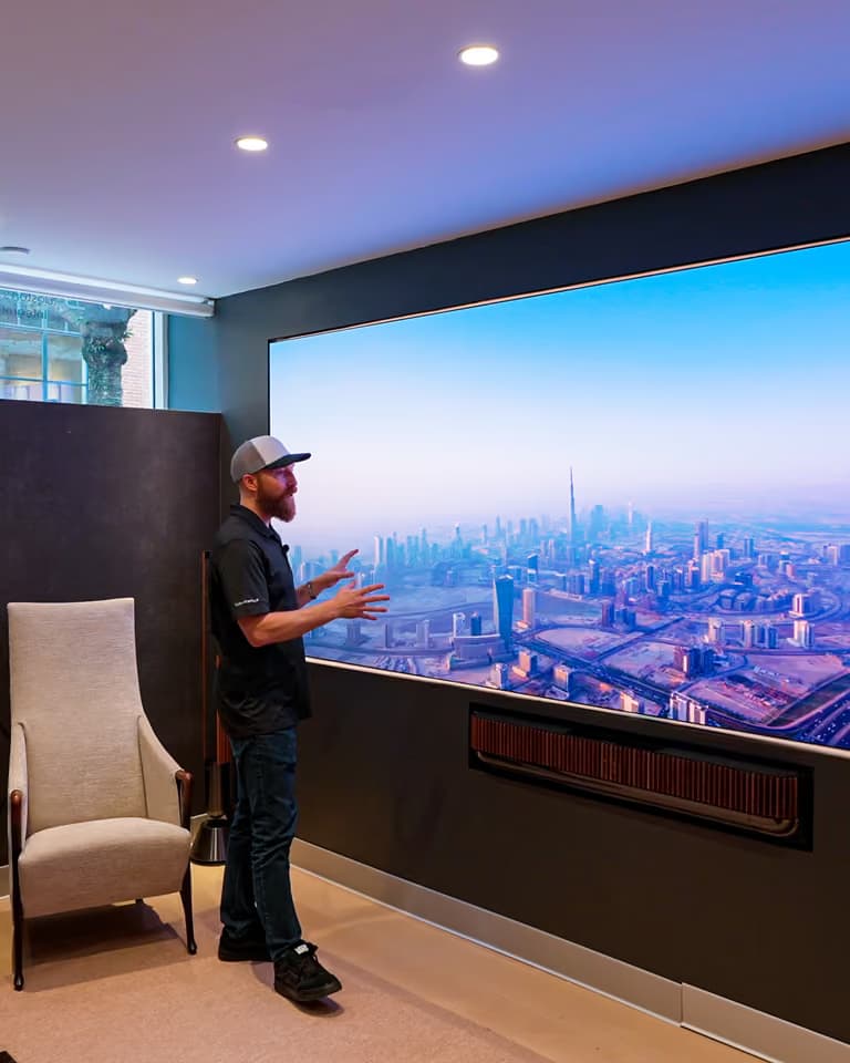 A man gesturing toward a MicroLED wall showing a cityscape